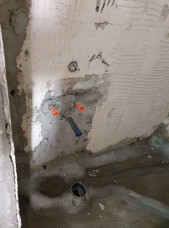 תשתיות אינסטלציה חשופות בחדר הרחצה לפני השיפוץ